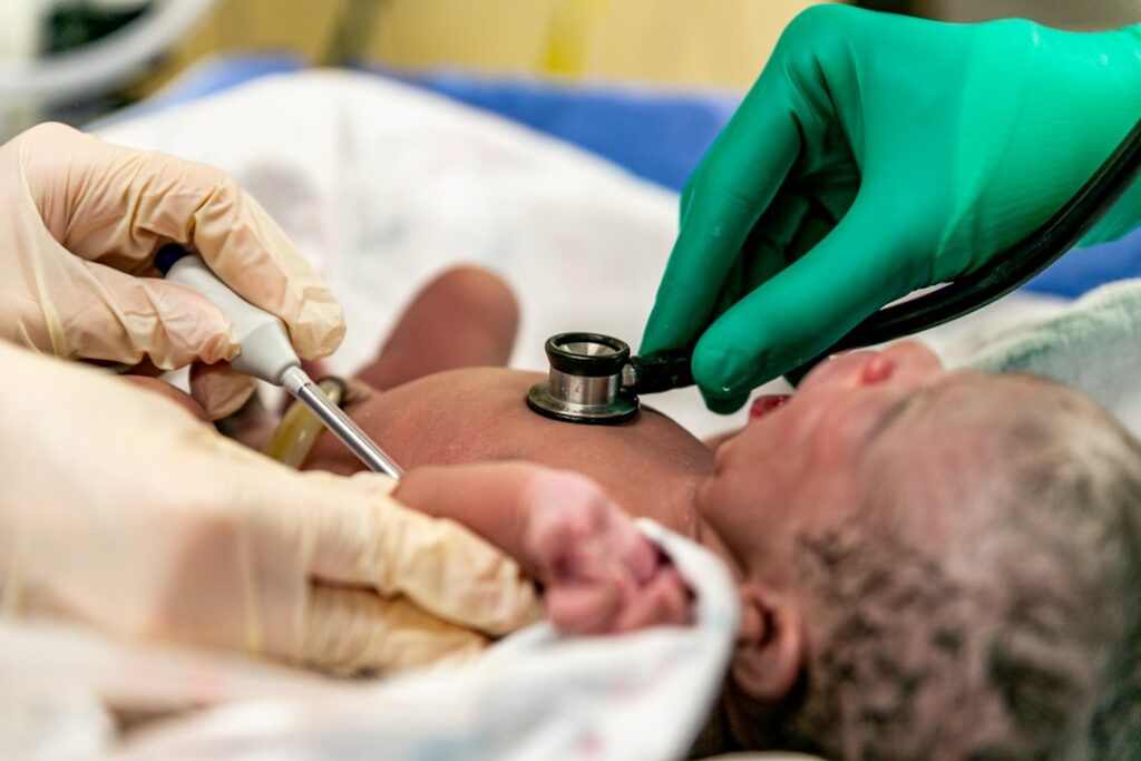 Newborn Baby Having Lungs and body temperature checked: doctors listen to a newborn's lung function while checking the body temperature in an operating room. A depiction of childbirth.